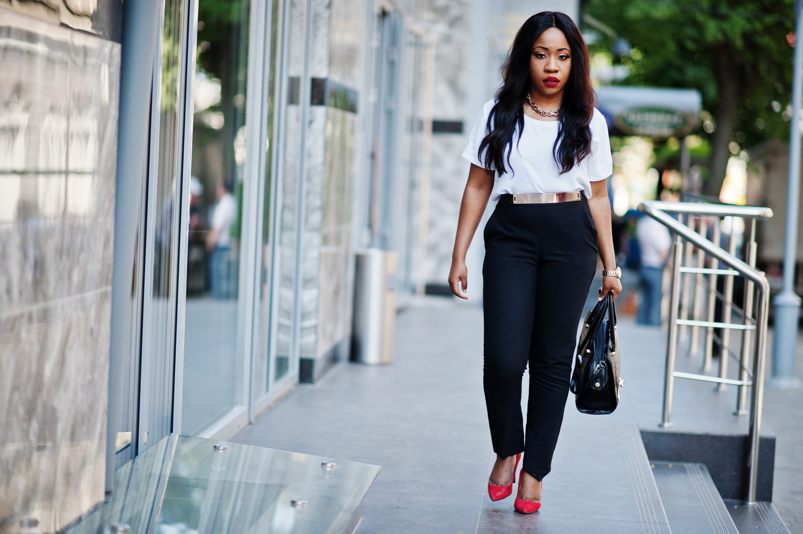 Stylish african american business woman with handbag on streets of city.