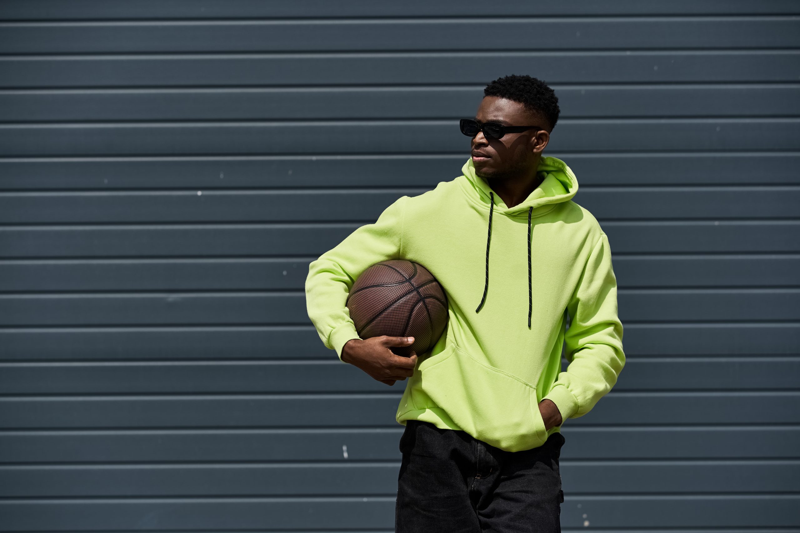 African American man in green hoodie holding basketball.